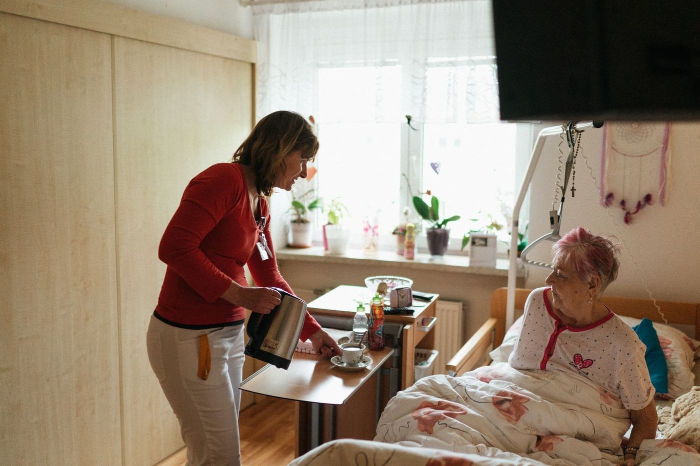 A carer sitting and talking gently with an older woman at home