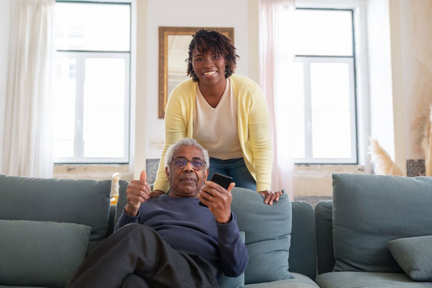 A friendly home carer supporting a smiling older man in his living room