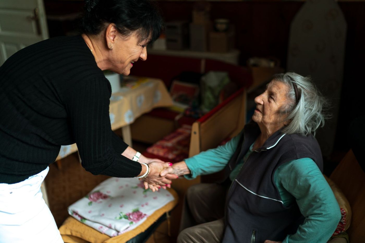A warm live-in carer greeting a smiling older woman in her own home