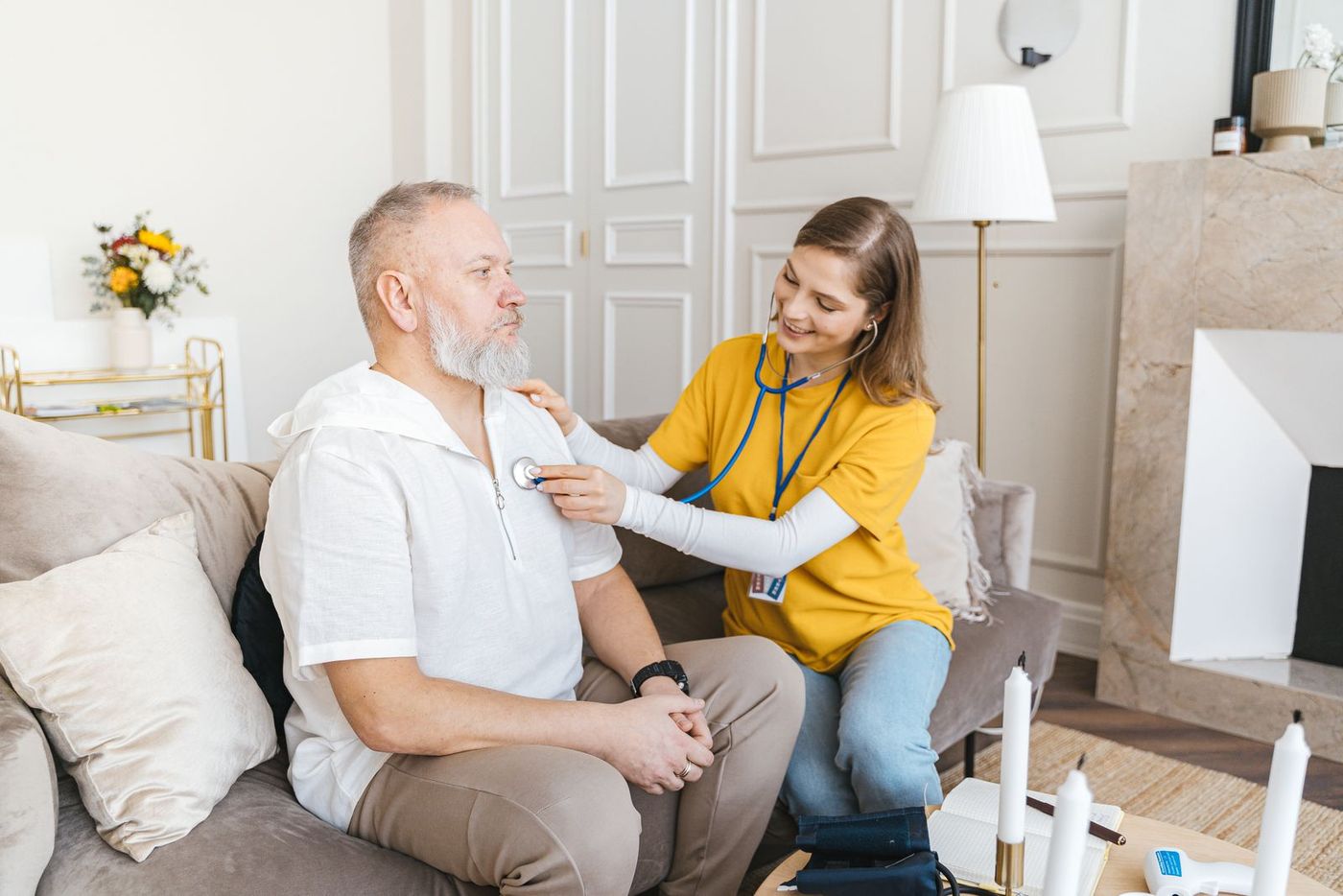 An NMC-registered nurse carrying out a gentle home check-up with an older patient in a comfortable living room